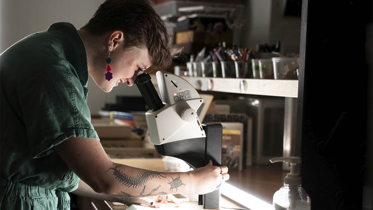 A woman looks into a microscope in a laboratory.