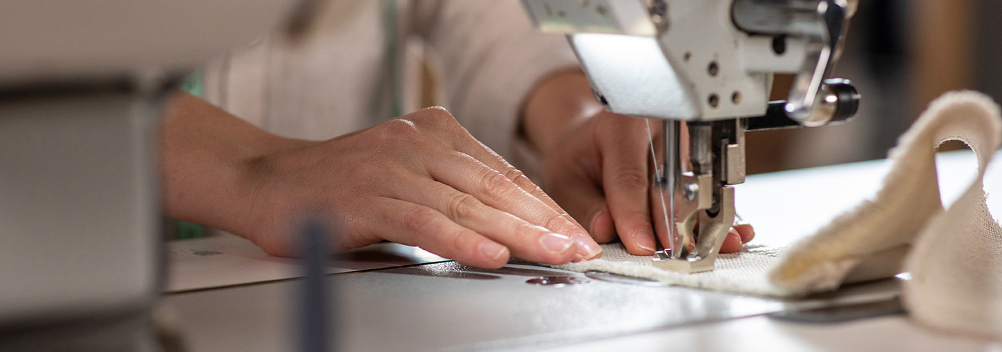 Image of a person’s hands on a sewing machine.