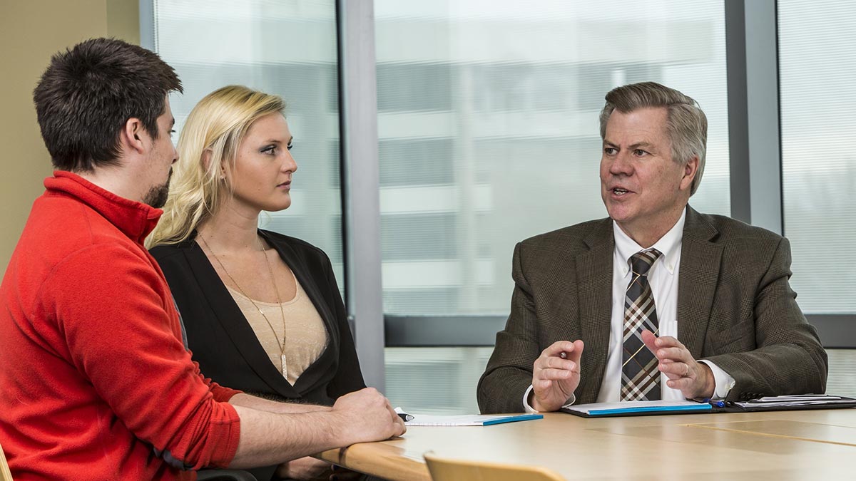 Three people sitting at a table in discussion.