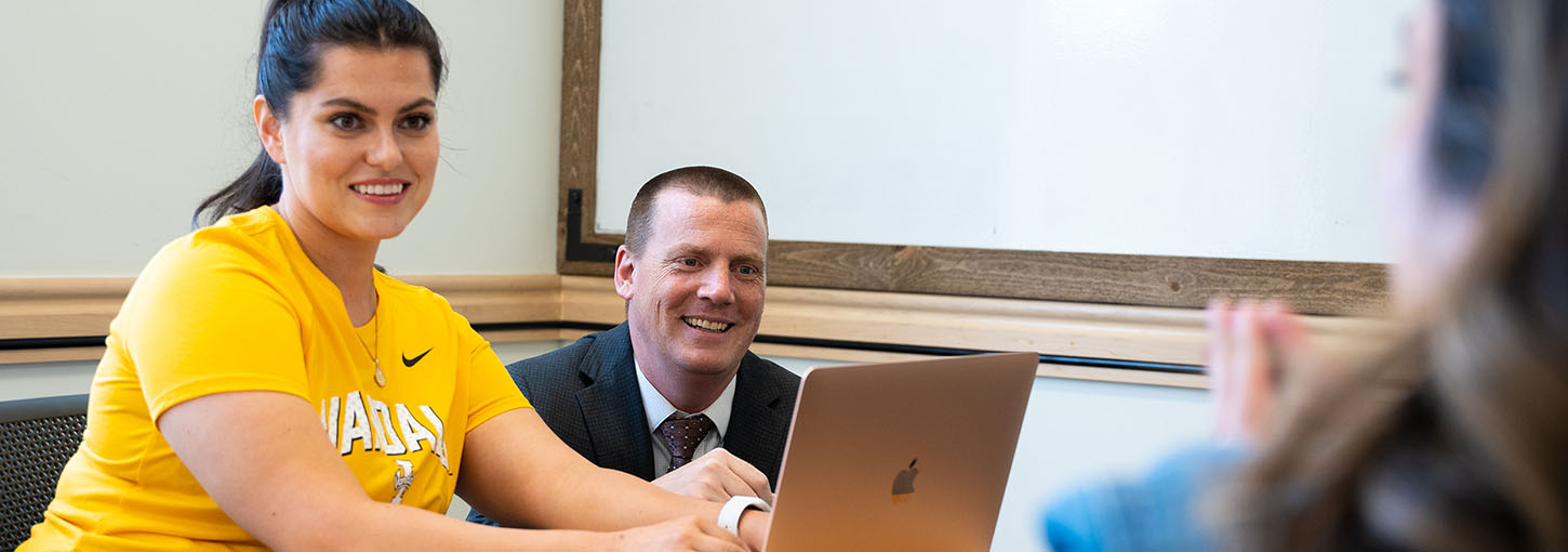 Idaho Law ranked Top Law School for Intellectual Property Law. Image features professor overseeing student working on laptop. 