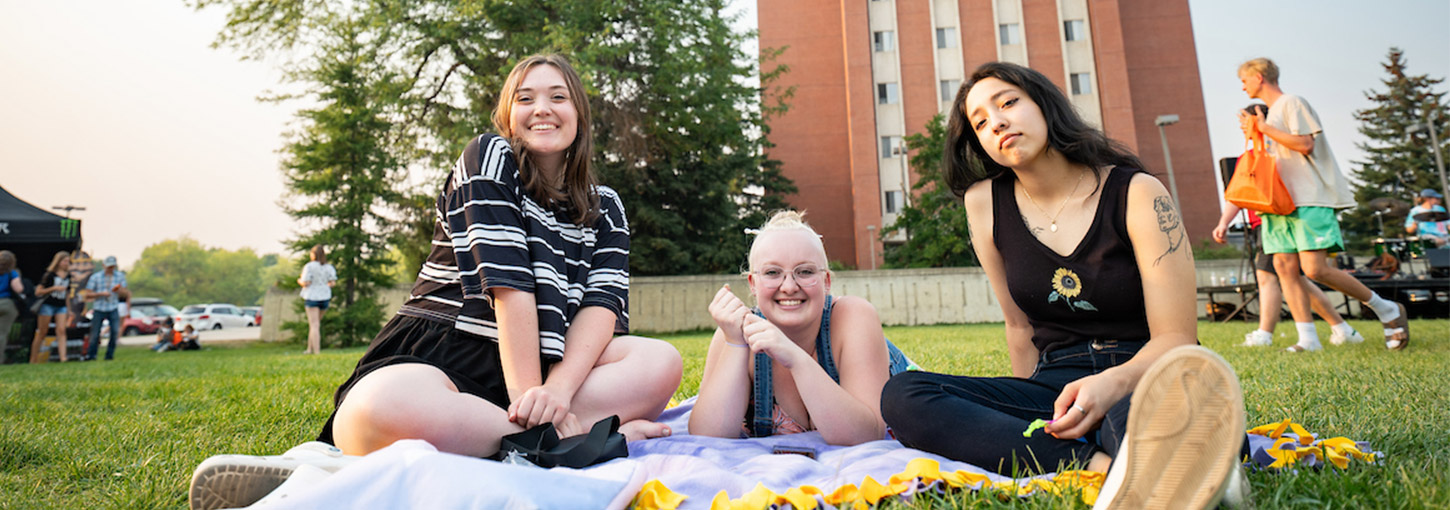 3 girls sitting on a lawn at the U of I campus