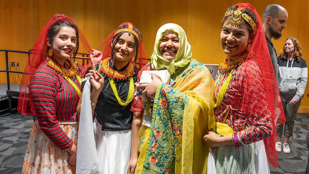 Four women pose in colorful saris