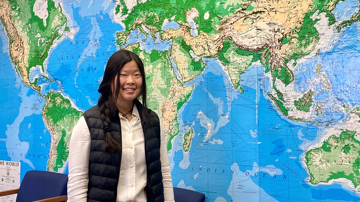 Woman standing in front of world map.