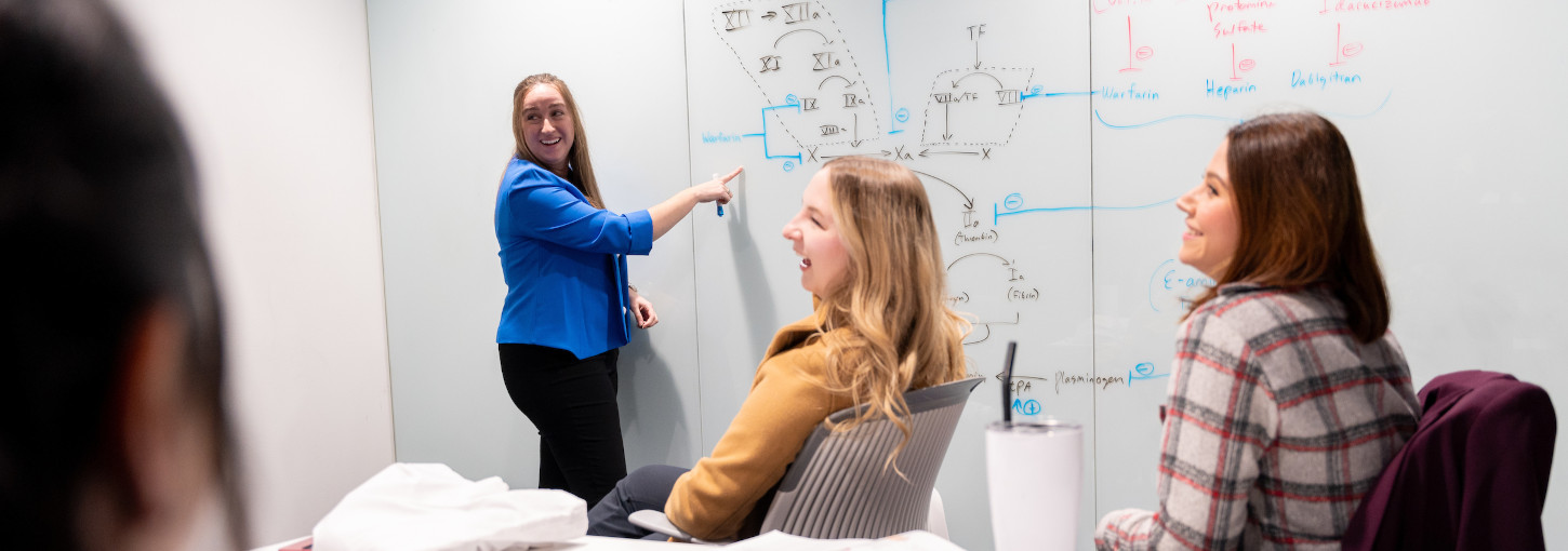 Four girls laughing and studying at a whiteboard.