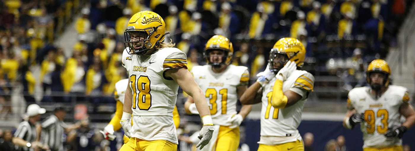 Five football players in white and gold uniforms.