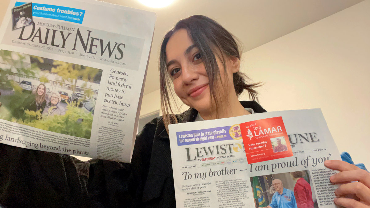 Photo of woman holding two newspapers.