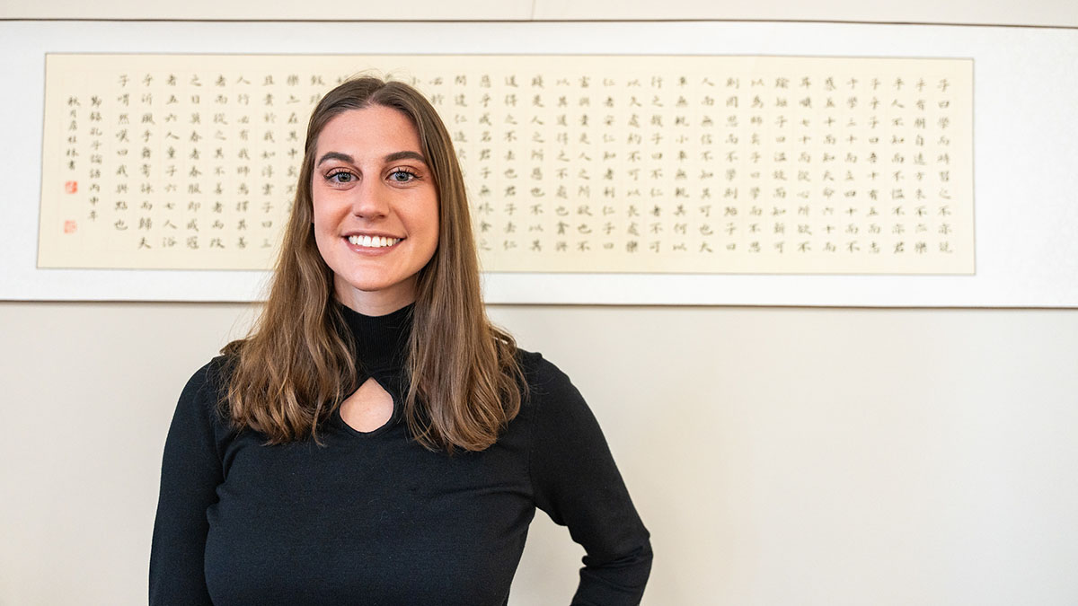 Woman stands in front of art with Japanese characters.